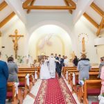 A bride and groom walk down the aisle after their wedding ceremony in a colorful church.